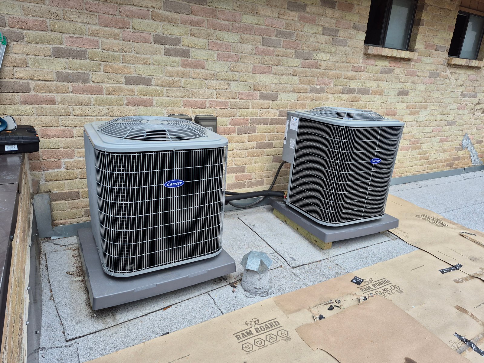 Two outdoor central air conditioning units installed on concrete pads next to a building, ready for operation.